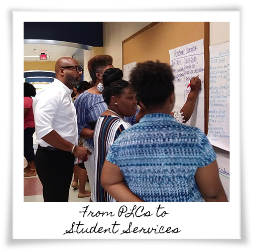 Dr. Dickey with a group of women writing on a wall chart for school improvement