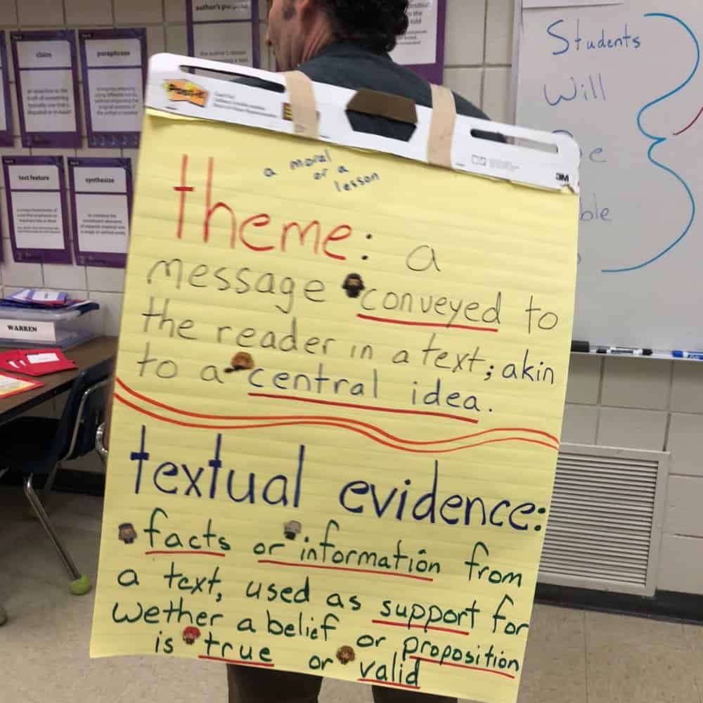 A man standing with a chart behind his back showing textual evidence