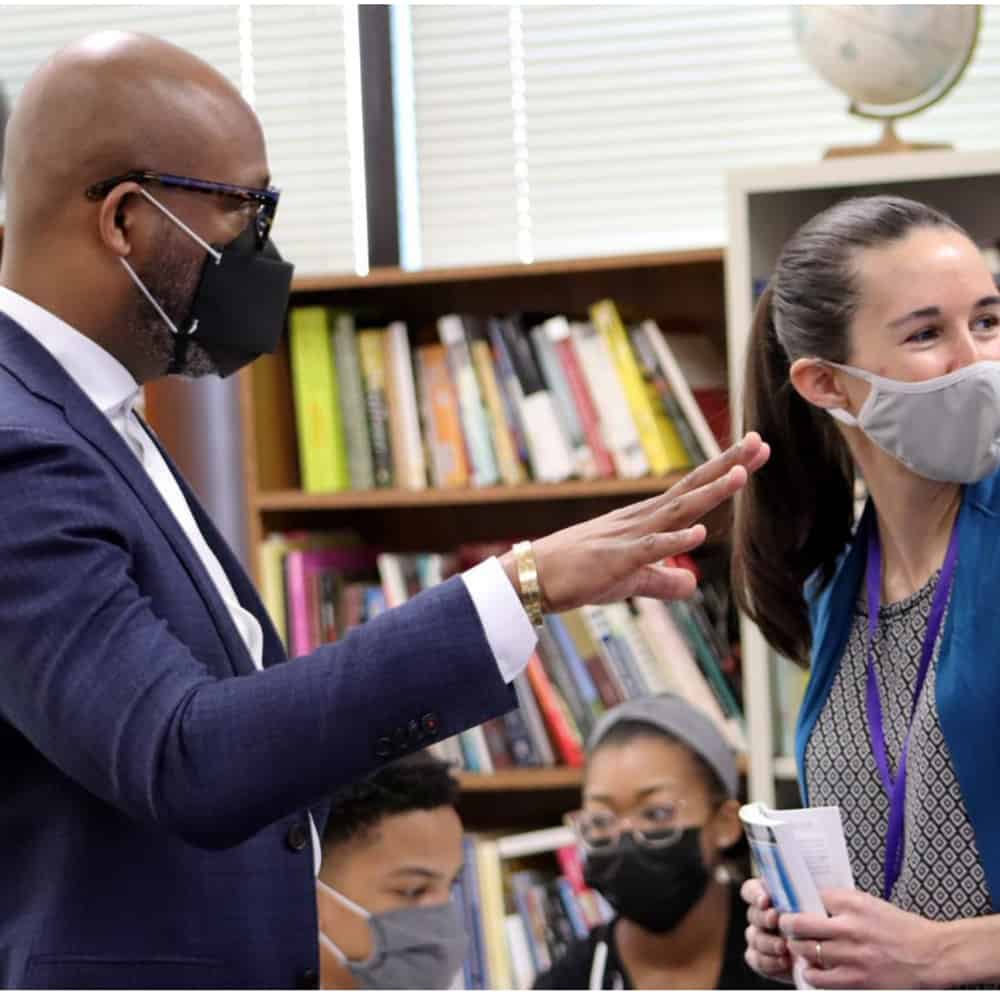 Dr. Dickey speaking with a woman with ponytail and face mask in a library
